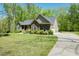 Inviting single-story home featuring stone accents, well-maintained landscaping, and a paved driveway on a sunny day at 4057 Mackenzie Dr, Haw River, NC 27258