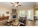 Comfortable living room with a stone fireplace, wood floors, a ceiling fan, and natural light at 4057 Mackenzie Dr, Haw River, NC 27258