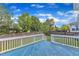 Relaxing backyard deck area with a blue floor and white railings overlooking a well-maintained lawn and fence at 4252 Rockdell Hall St, Raleigh, NC 27616