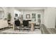 Contemporary dining area with a long wooden table, modern black chairs, and a view into the bright, white kitchen at 472 Carolina Springs Blvd, Apex, NC 27539