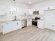 Modern kitchen with white cabinets, granite countertops, stainless steel appliances, and wood-look flooring at 48 S Grace Way, Henderson, NC 27537