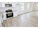 Bright kitchen space featuring white cabinetry, stainless appliances, and a view to the open living area at 48 S Grace Way, Henderson, NC 27537