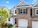 Townhome with stone detail and white siding, featuring an attached garage and manicured landscaping at 5518 Jessip St, Morrisville, NC 27560