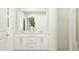 A stylish bathroom features white cabinets, a decorative mirror, and a vase of greenery at 617 Cassa Clubhouse Way, Knightdale, NC 27545