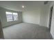 Expansive bedroom featuring soft gray carpeting, a large window, and neutral-colored walls at 621 Cassa Clubhouse Way, Knightdale, NC 27545