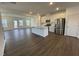 Open-concept kitchen with white cabinets, stainless steel appliances, an island, and wood flooring at 621 Cassa Clubhouse Way, Knightdale, NC 27545