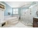 Bright bathroom featuring marble tiled floors, a soaking tub with steps, and glass shower at 658 Bennett Mountain Trce, Chapel Hill, NC 27516