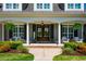 Inviting front porch with white columns, black shutters, seating, and decorative wreaths on the double front doors at 658 Bennett Mountain Trce, Chapel Hill, NC 27516