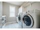 Bright laundry room with white cabinets, a window, and marble tile floors at 658 Bennett Mountain Trce, Chapel Hill, NC 27516