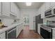 Bright galley kitchen featuring white cabinets, stainless steel appliances, and tile flooring at 707 Southshore Pkwy, Durham, NC 27703