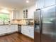 Well-lit kitchen with stainless steel refrigerator and white cabinets, and granite countertops at 713 Macon Pl, Raleigh, NC 27609