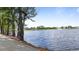 Scenic view of a serene pond lined with lush trees and a paved walkway at 72 S Grey Abbey Dr, Clayton, NC 27527