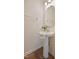 Charming half-bath featuring pedestal sink with modern fixtures, mirror, and decorative accents and wood floors at 72 S Grey Abbey Dr, Clayton, NC 27527
