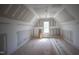 Unfinished attic space with ample potential, featuring a dormer window for natural light and ventilation at 7301 Wexford Woods Ln, Wake Forest, NC 27587