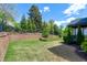 Well-kept backyard featuring a green lawn and a landscaped retaining wall with manicured greenery and trees at 7510 Latteri Ct, Raleigh, NC 27613