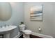 Stylish powder room with a pedestal sink, round mirror, and elegant fixtures at 7510 Latteri Ct, Raleigh, NC 27613