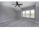 Spacious bedroom featuring a modern ceiling fan, soft carpet, and bright natural light from large windows at 7510 Latteri Ct, Raleigh, NC 27613