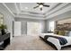 Large main bedroom with an ensuite bathroom, a tray ceiling, and soft carpet at 7510 Latteri Ct, Raleigh, NC 27613