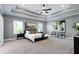 Spacious main bedroom with a tray ceiling, carpeted floor, and large windows at 7510 Latteri Ct, Raleigh, NC 27613