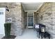 Charming covered entryway with a welcoming wreath, stone detailing, and a cozy bench at 769 Ashley Woods Dr, Gibsonville, NC 27249