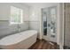 Elegant bathroom featuring a soaking tub, closet access, and natural light from a window at 7955 Midnight Ln, Wake Forest, NC 27587