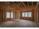 Unfinished living room featuring exposed wooden framing, electrical wiring, and multiple windows at 7961 Wexford Waters Ln, Wake Forest, NC 27587