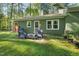 Exterior of the home with patio furniture, surrounded by a lush lawn, trees, and vibrant greenery at 8 Bluebell Ct, Durham, NC 27713