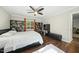 Sunlit bedroom featuring built-in bookshelves, a ceiling fan, hardwood floors, and windows overlooking the lush landscape at 8 Bluebell Ct, Durham, NC 27713
