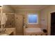 Bathroom showing a shower and separate soaking tub under a bright window at 901 Hollymont Dr, Holly Springs, NC 27540