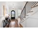 Inviting foyer featuring hardwood floors, a staircase with black metal railing, and an arched front door at 928 Lily Claire Ln, Fuquay Varina, NC 27526