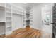 Spacious walk-in closet with custom shelving and wood flooring and doorway to the bedroom at 928 Lily Claire Ln, Fuquay Varina, NC 27526