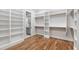 Spacious walk-in closet with custom shelving and wood flooring with doorway to the bathroom at 928 Lily Claire Ln, Fuquay Varina, NC 27526