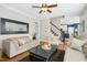 View of the living room with hardwood floors, comfortable seating, and an adjacent staircase and kitchen at 101 Silk Leaf, Cary, NC 27518