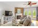 Cozy living room features a stone fireplace, ceiling fan, and access to the outdoor deck at 1029 Frank Page Dr, Cary, NC 27519