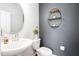 Stylish powder room featuring a pedestal sink, toilet, and decorative round shelving on a gray accent wall at 1036 S Fieldhaven Dr, Fuquay Varina, NC 27526