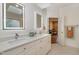 Bright bathroom with dual sinks, illuminated mirrors, and a doorway leading to the bedroom at 108 Monarch Way, Cary, NC 27518