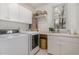 Well-lit laundry room features sink, washer, dryer, white cabinetry, shelving and window at 108 Monarch Way, Cary, NC 27518
