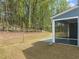 A view of the backyard with a screened in patio and a tiered retaining wall in a wooded setting at 1120 Copper Beech Ln, Wake Forest, NC 27587