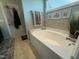 Soaking tub offers a relaxing experience with a view, complemented by decorative accents and fresh towels at 116 Polenta Fields Dr, Smithfield, NC 27577