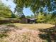 An exterior shot of a home displaying a large backyard shaded by trees and featuring a cozy outdoor seating area at 1317 Kelly Rd, Garner, NC 27529
