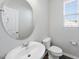 Well-lit half bathroom features round mirror, white sink, toilet, and window at 1335 Herb Garden Way, Apex, NC 27502