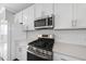 Modern kitchen with stainless steel appliances, quartz countertops, and white cabinetry at 1335 Herb Garden Way, Apex, NC 27502