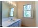 Bright bathroom featuring a large mirror, vanity sink, and a window with shutters at 1408 Edgebrook Dr, Garner, NC 27529