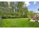 Lush backyard featuring a manicured lawn, mature trees, and outdoor seating at 144 Cobble Ridge Dr, Pittsboro, NC 27312