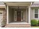Home's cozy front porch with brick accents, decorative columns, and a beautiful wood front door with glass detailing at 144 Cobble Ridge Dr, Pittsboro, NC 27312