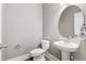 Half bathroom with a toilet, pedestal sink, and a decorative round mirror at 157 Maplewood Dr, Sanford, NC 27332