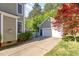 View of the side yard featuring the detached garage with a basketball hoop near a beautiful red maple tree at 161 Fort Jackson Rd, Morrisville, NC 27560