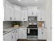 Kitchen boasts stainless steel appliances, granite countertops, gray backsplash, and white cabinets at 166 Old Field Loop Loop, Sanford, NC 27332