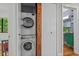 Laundry closet with stacked washer and dryer and view into the updated bathroom at 1804 N Alston Ave, Durham, NC 27701