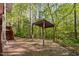 Landscaped backyard with stone pavers and a covered pavilion surrounded by lush trees at 195 Nicks W Bnd, Pittsboro, NC 27312